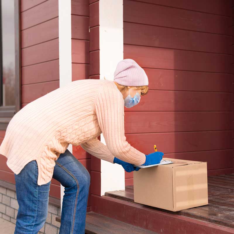 a woman leaves a package on a porch