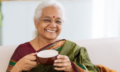 an elderly woman with a mug, smiling for the camera