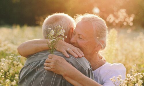 an elderly couple hugging in a field